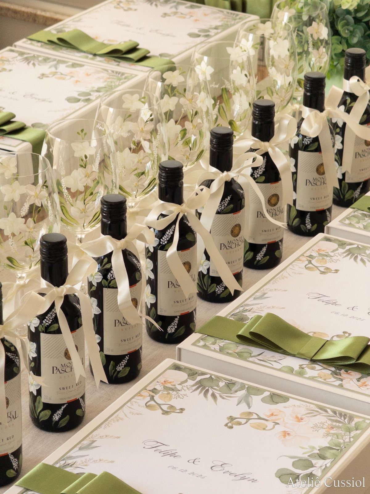 Small wine bottles with white ribbons and champagne glasses on a wedding table.