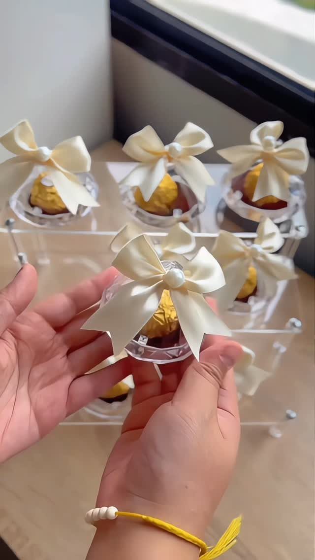 Gold-wrapped chocolate truffles in clear containers with white satin bows and pearls.