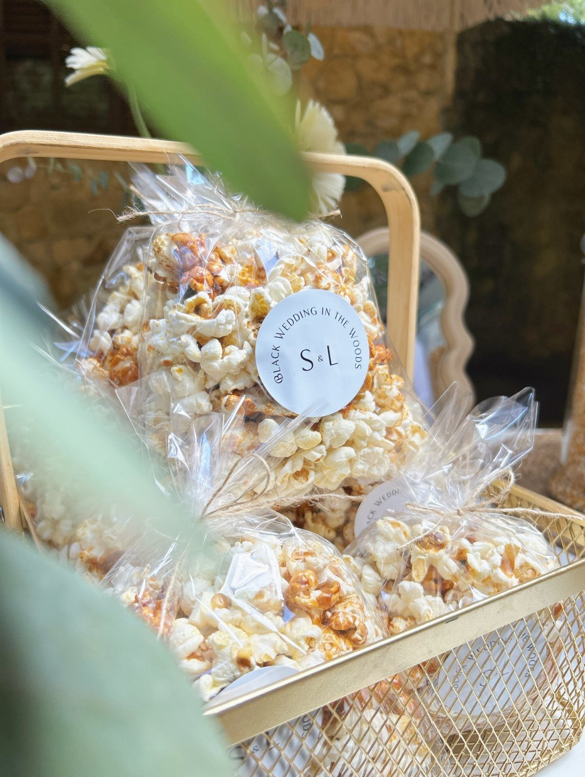 Caramel popcorn bags with custom wedding labels in a woven basket