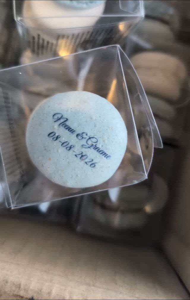 Light blue macaron with personalized names and date in a clear plastic box
