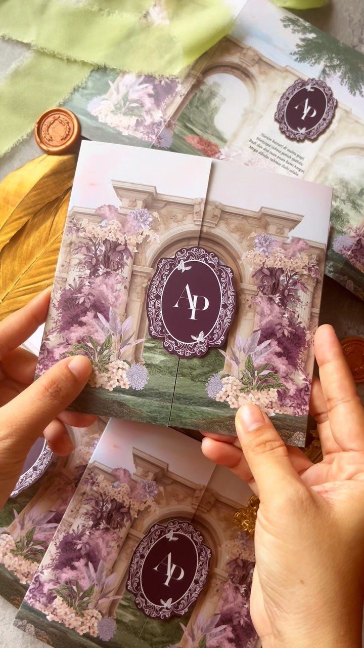 Wedding invitation featuring a stone archway decorated with purple floral arrangements and monogram.