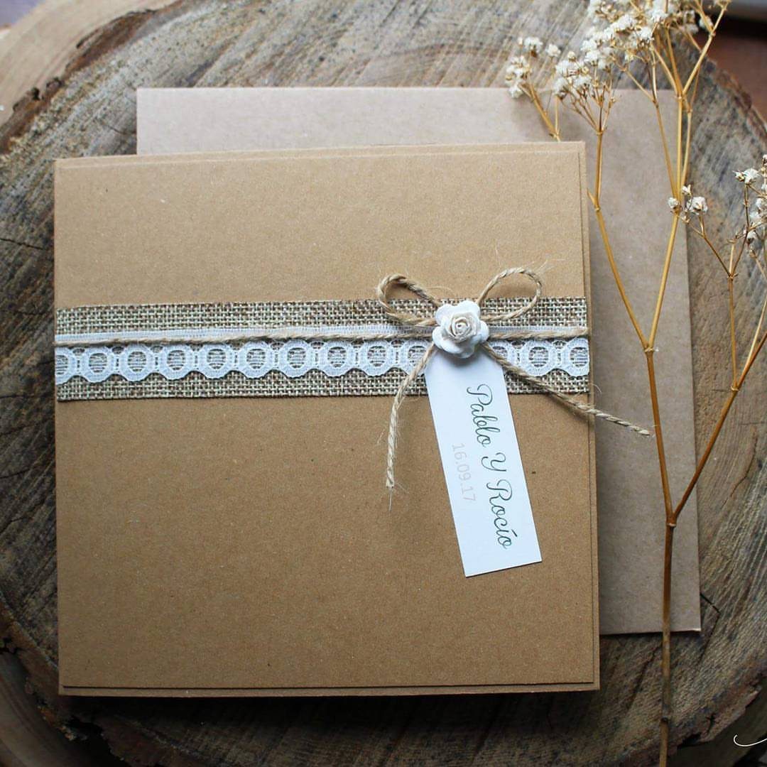 Brown kraft paper wedding invitation wrapped in burlap and lace on a wood slice