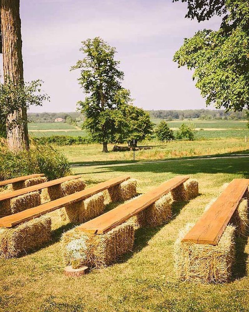 Wooden plank benches resting on hay bales in a grassy outdoor field.