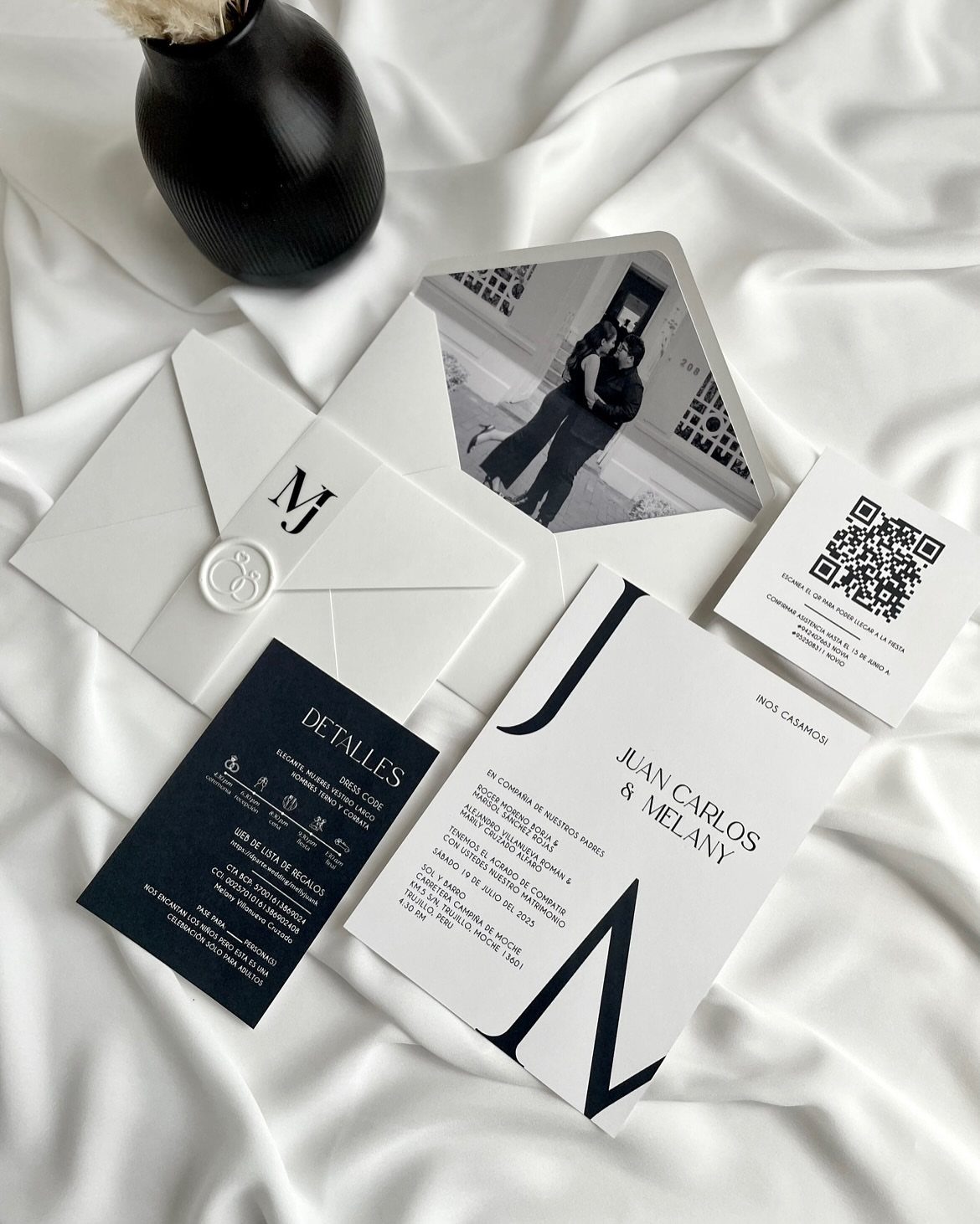 Wedding invitation set with bold black typography and monogram on white satin fabric