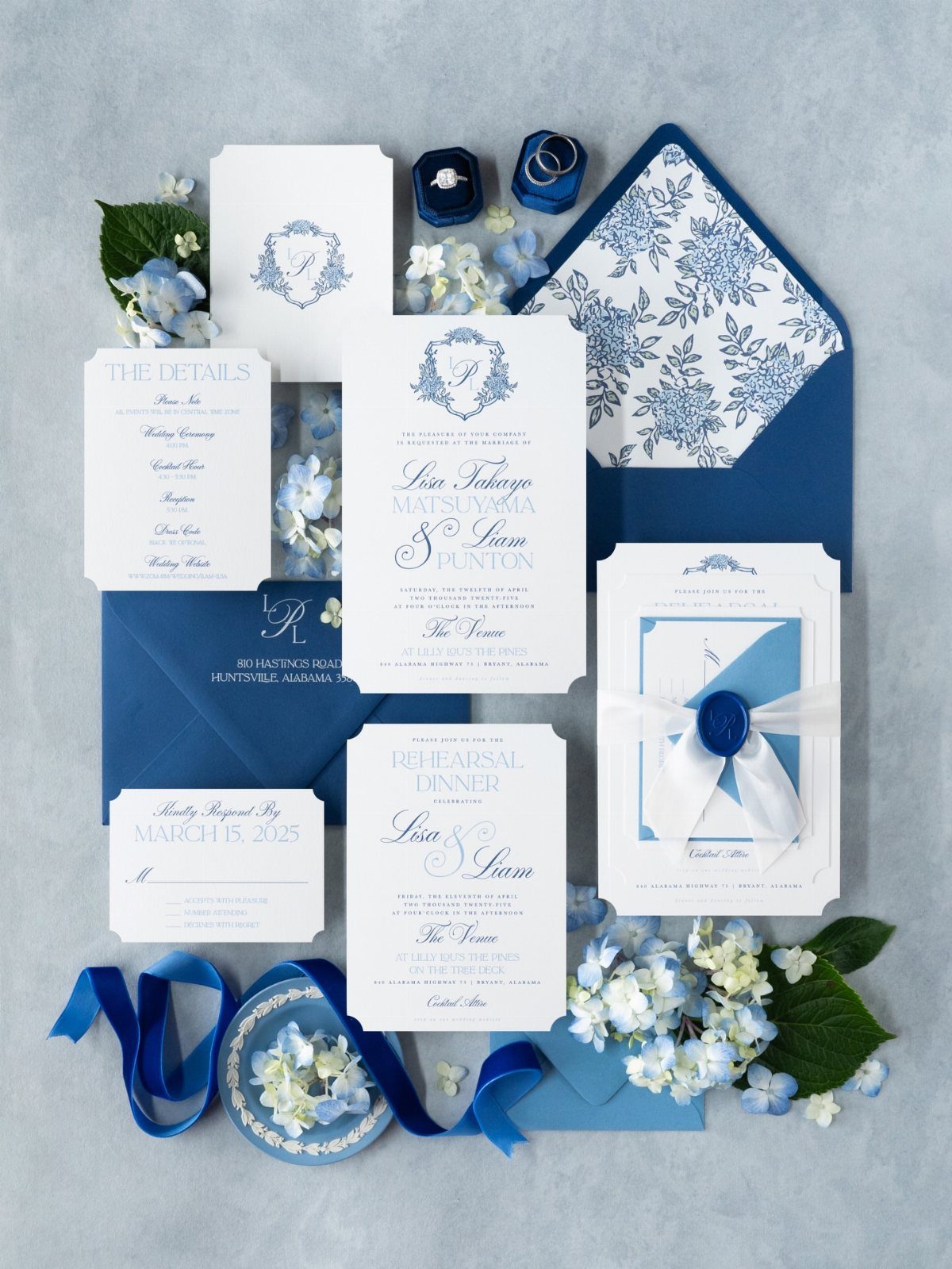 White wedding invitation suite with blue calligraphy, navy envelopes, and blue hydrangea flowers.