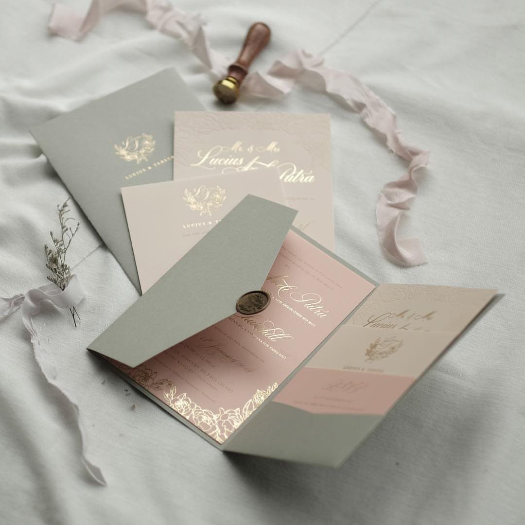 Wedding invitations in sage green and blush pink with gold foil and wax seal.