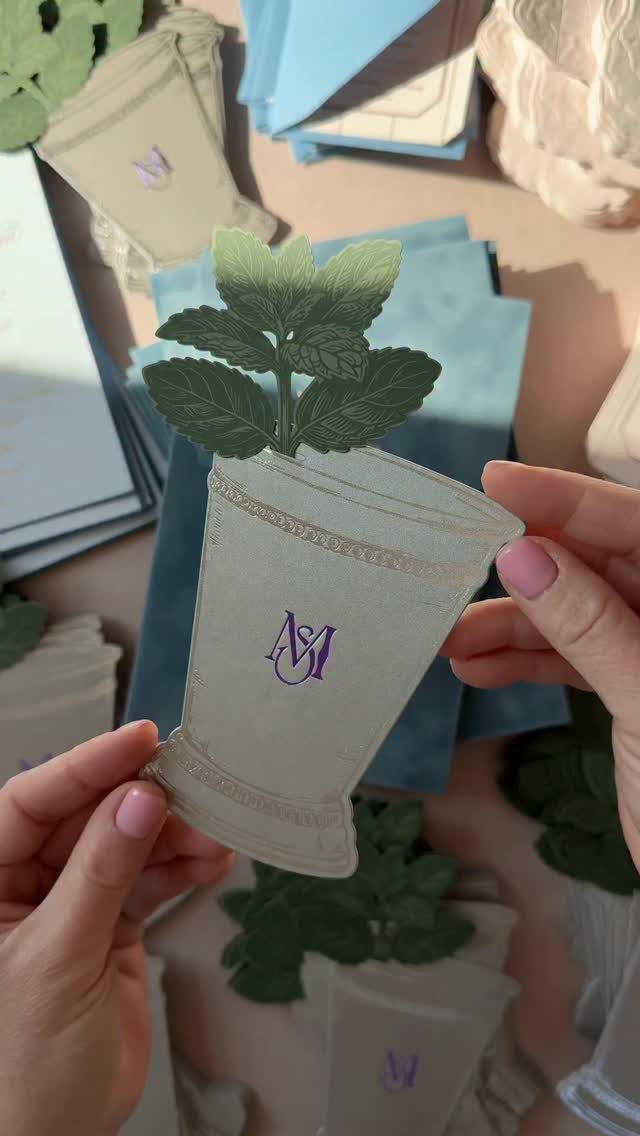 Die-cut wedding invitation shaped like a cocktail glass with green mint leaves and monogram.