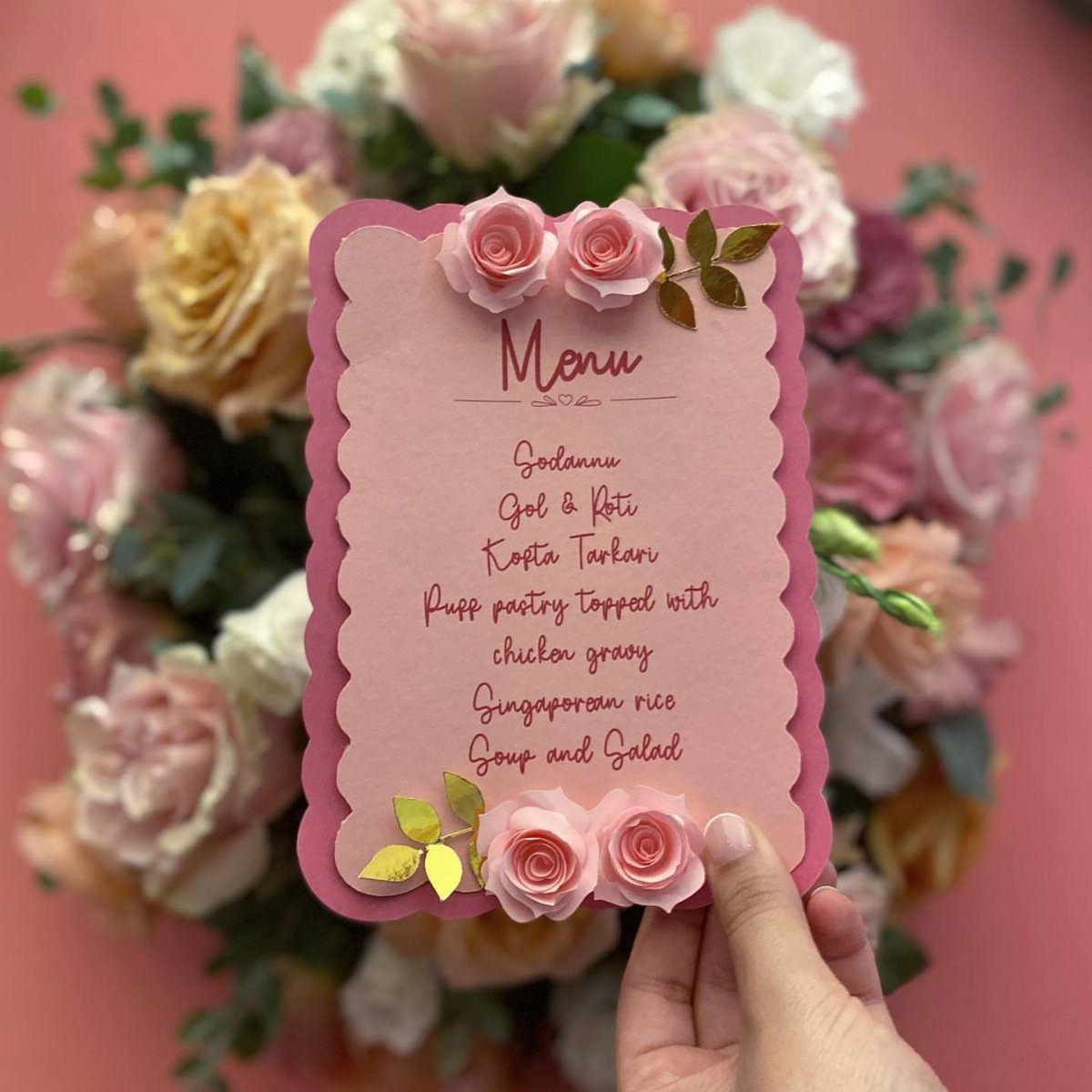 Pink scalloped menu card with 3D roses held against a floral background