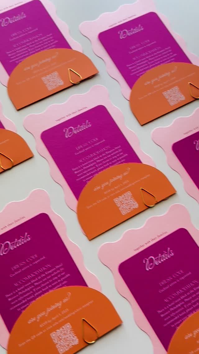 Pink and purple wedding detail cards with orange inserts and gold paperclips.