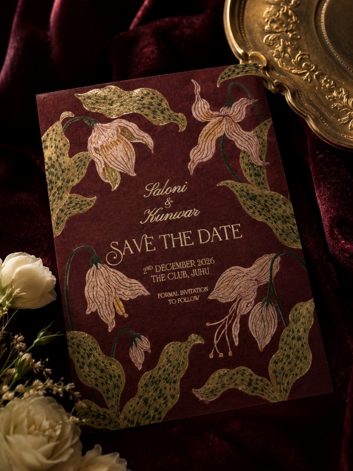 Burgundy wedding invitation with botanical flower illustrations resting on red velvet fabric