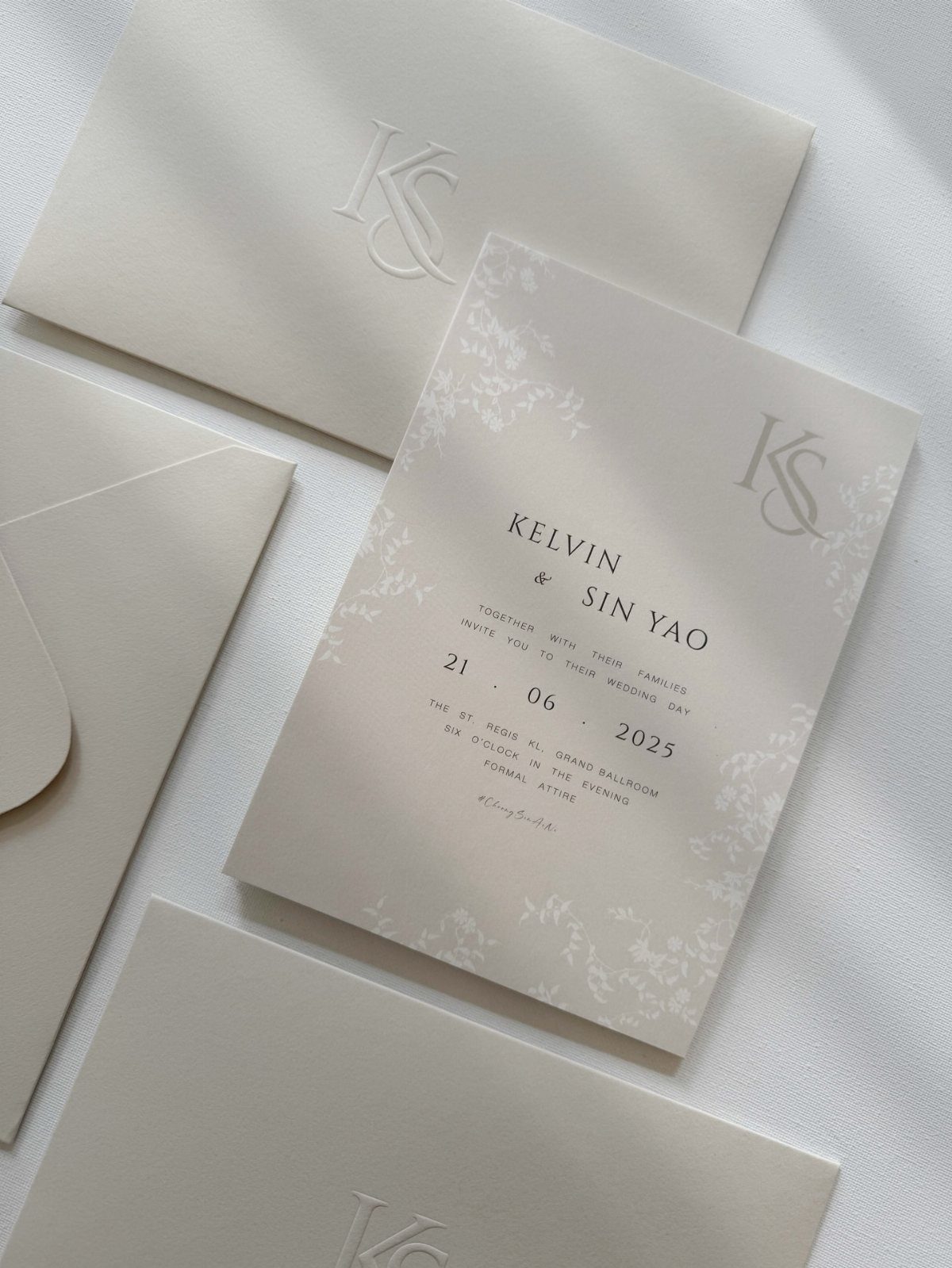 White wedding invitation suite with black typography and embossed monogram envelopes.