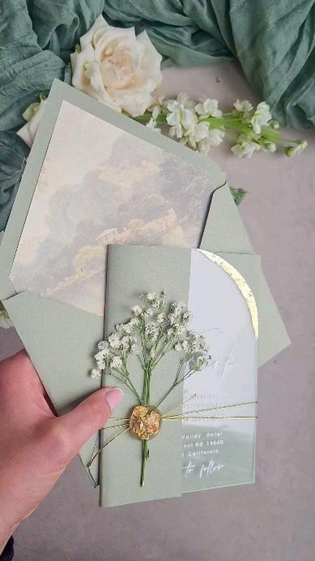 Sage green wedding invitation with white baby's breath and gold foil details.