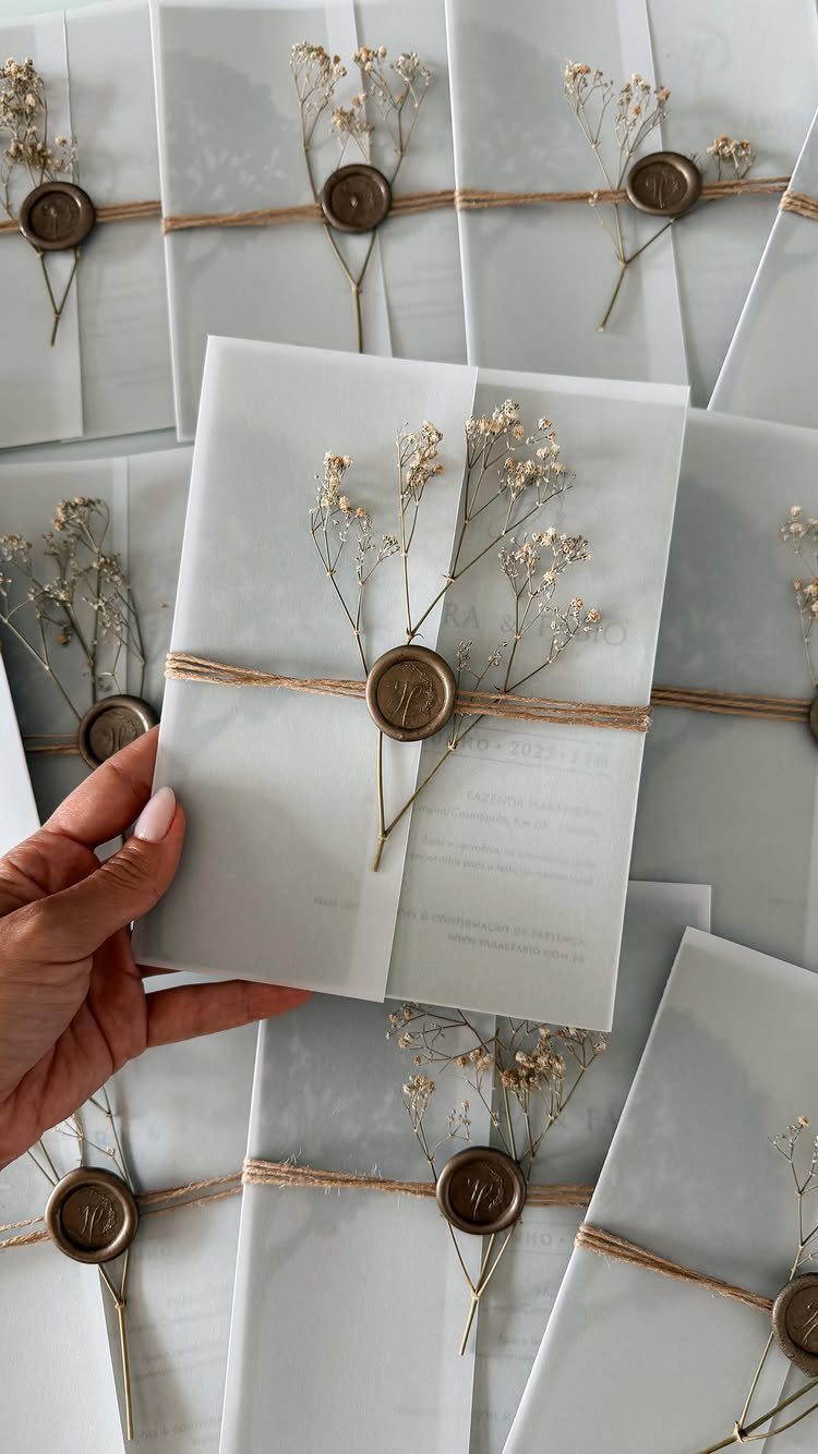 White wedding invitation wrapped in brown twine with a gold wax seal and dried flowers