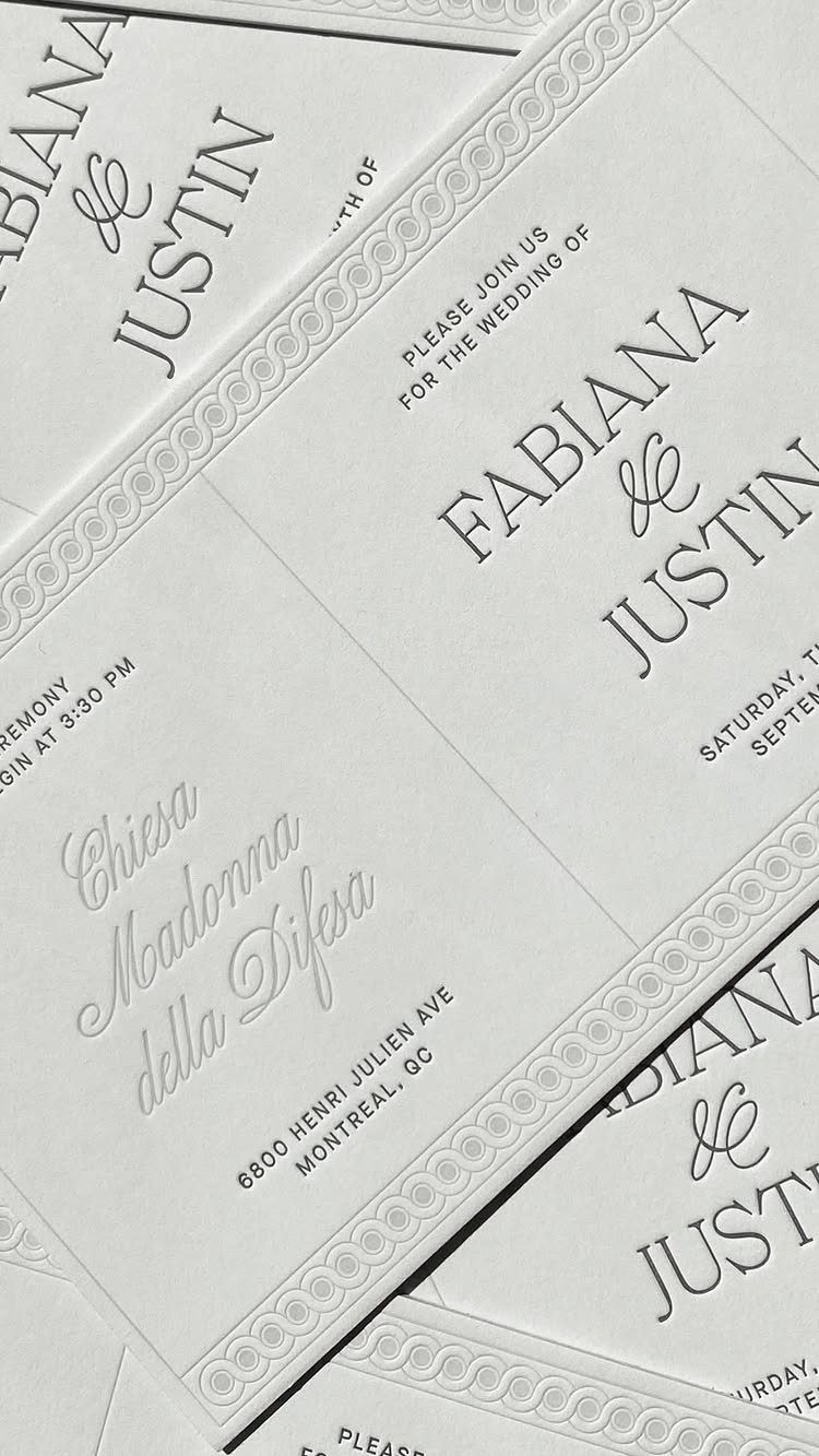 White wedding invitation cards with elegant black text and embossed decorative borders.