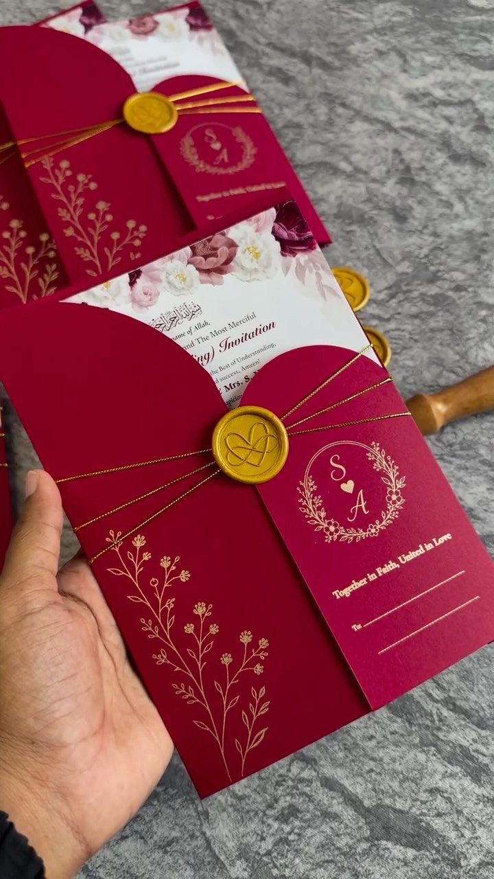 Deep red wedding invitation with gold foil details and a gold wax seal.