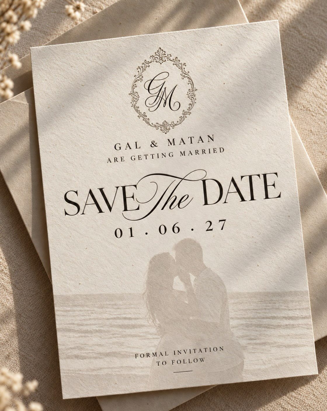 Save the date card with a faded beach photo of a couple embracing.