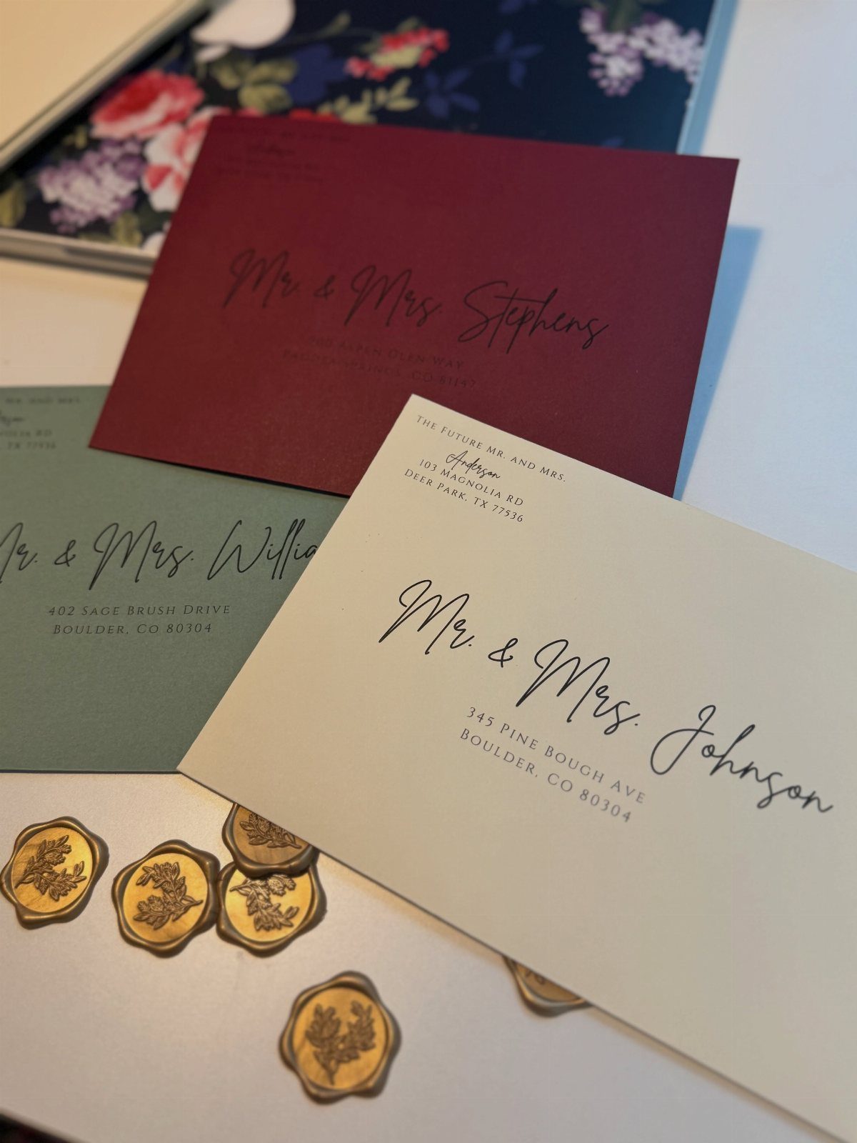 Wedding invitation envelopes in autumn colors with gold wax seals on white surface