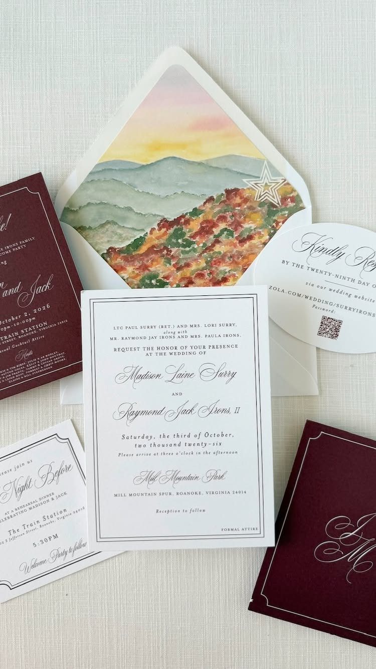 Wedding invitation suite with a watercolor mountain landscape envelope liner and burgundy accents.