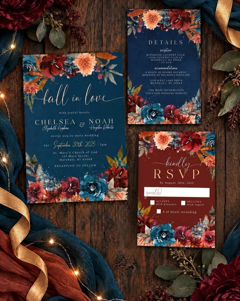 Wedding invitation suite with floral borders on a dark wooden background with ribbons.