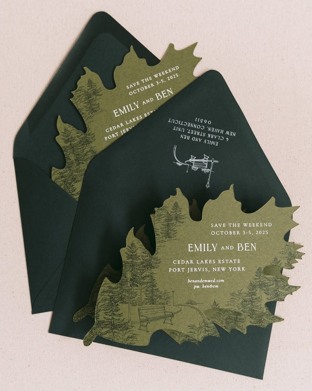 Die-cut forest landscape wedding invitations in olive green tucked into dark green envelopes.