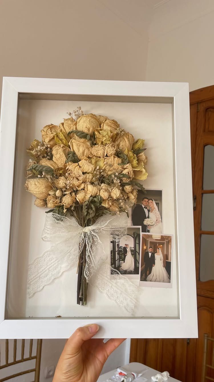 Dried wedding bouquet and couple photos preserved inside a white shadow box frame