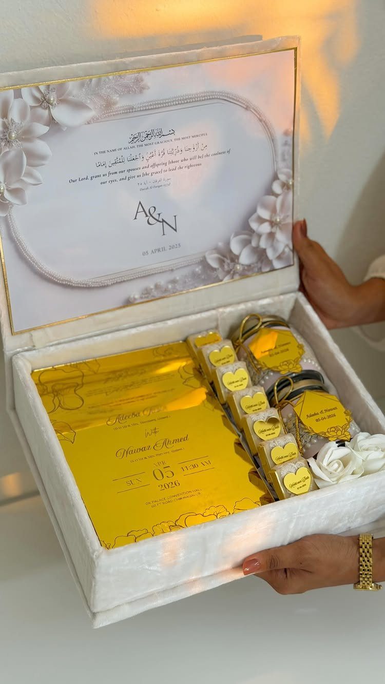 White velvet wedding keepsake box containing a gold invitation and small gift jars.
