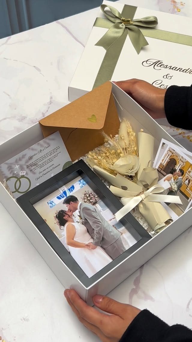 White wedding keepsake box containing a framed photo, dried flowers, and invitations.