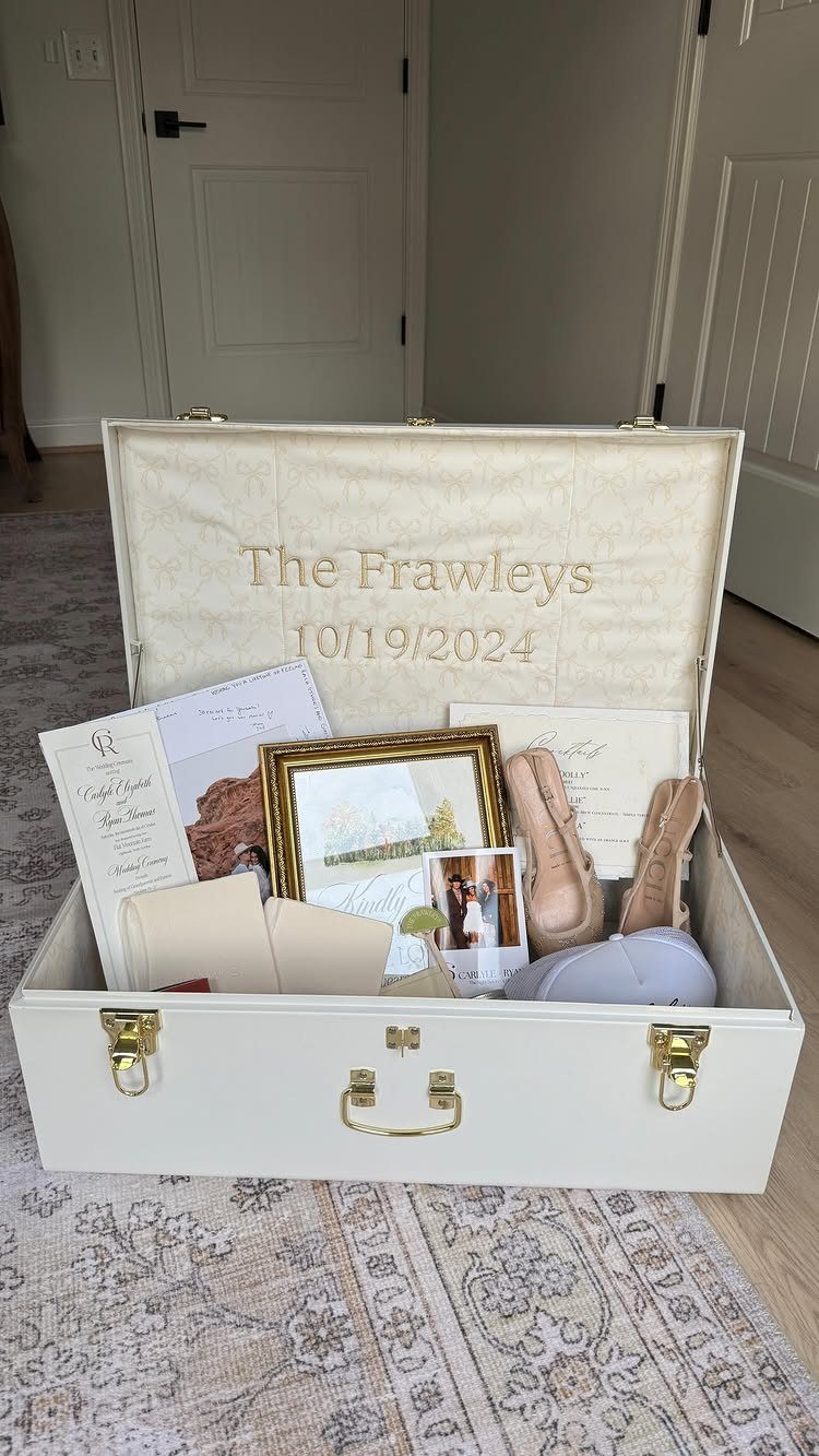 White wedding memory trunk filled with shoes, photos, and invitations on a rug