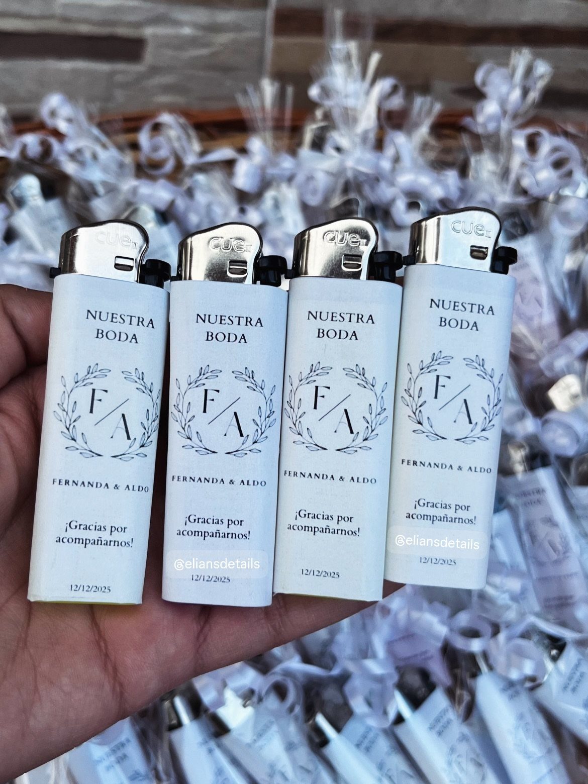 Four white custom wedding lighters with floral labels held in a person's hand.