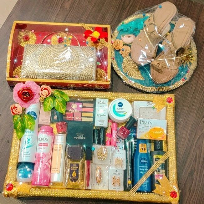 Gift trays containing skincare products, makeup, a gold clutch, and beige heeled sandals.