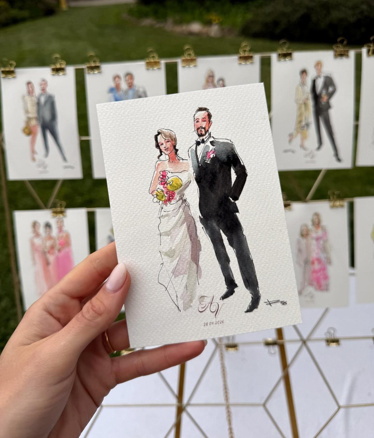 Watercolor illustration of a wedding couple held in front of other guest sketches.
