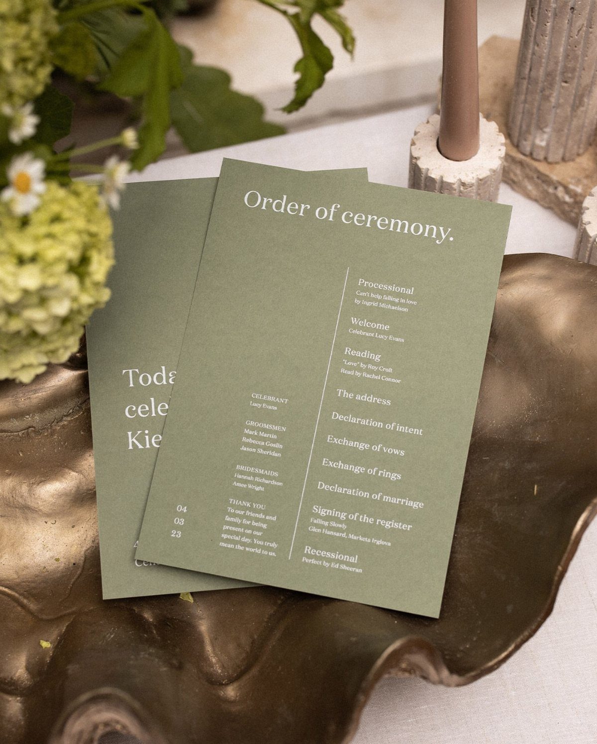 Sage green wedding programs on a gold tray showing the order of ceremony.