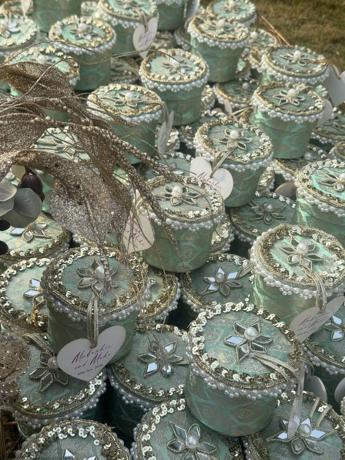 Mint-green ornate favor containers with beaded lids and heart-shaped tags for weddings.