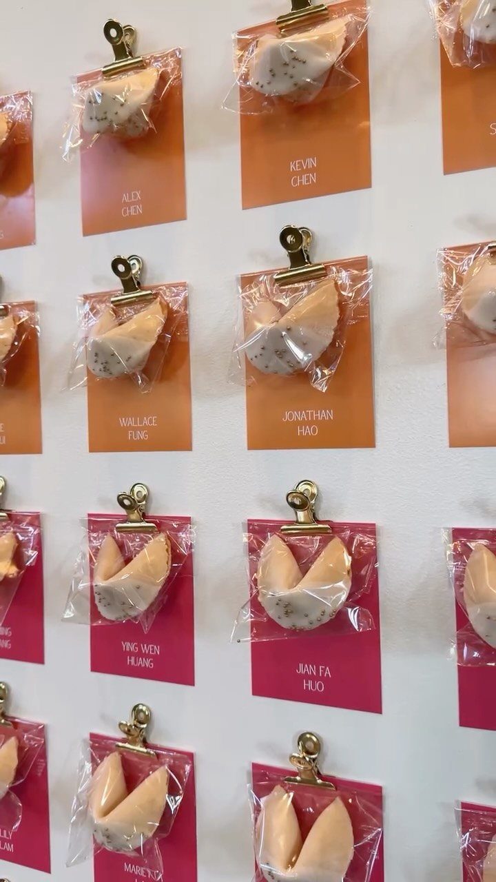 Fortune cookies in plastic bags clipped to colorful name cards on a wall.