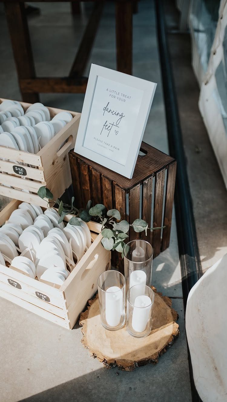 White flip-flops in wooden crates with a dancing feet sign and candles.