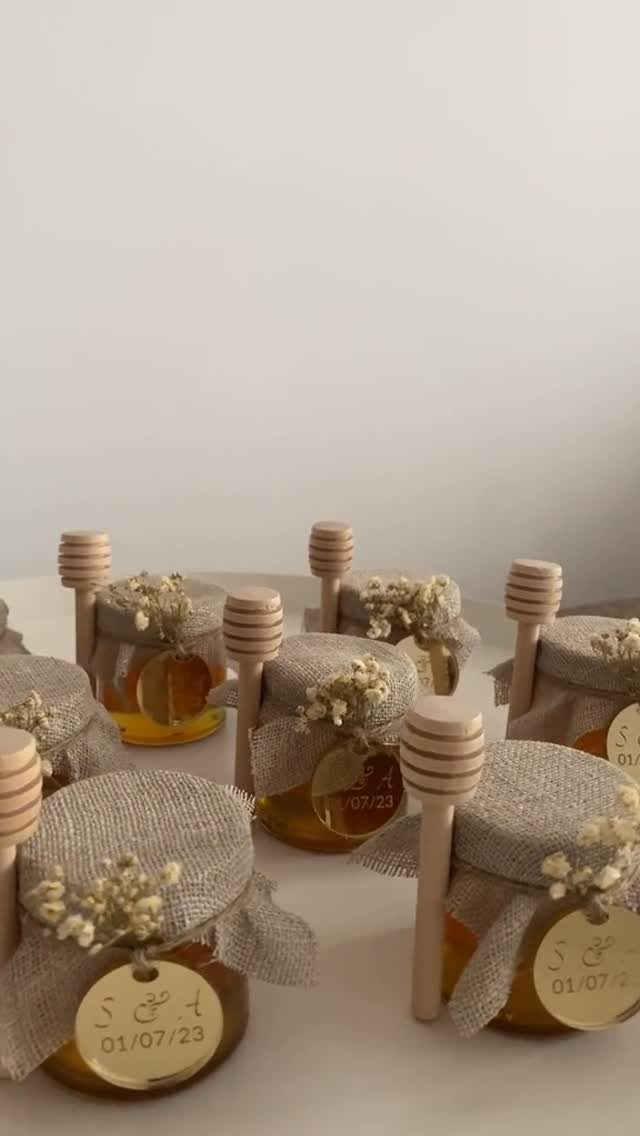 Small honey jars with burlap lids, wooden dippers, and personalized wedding date tags.