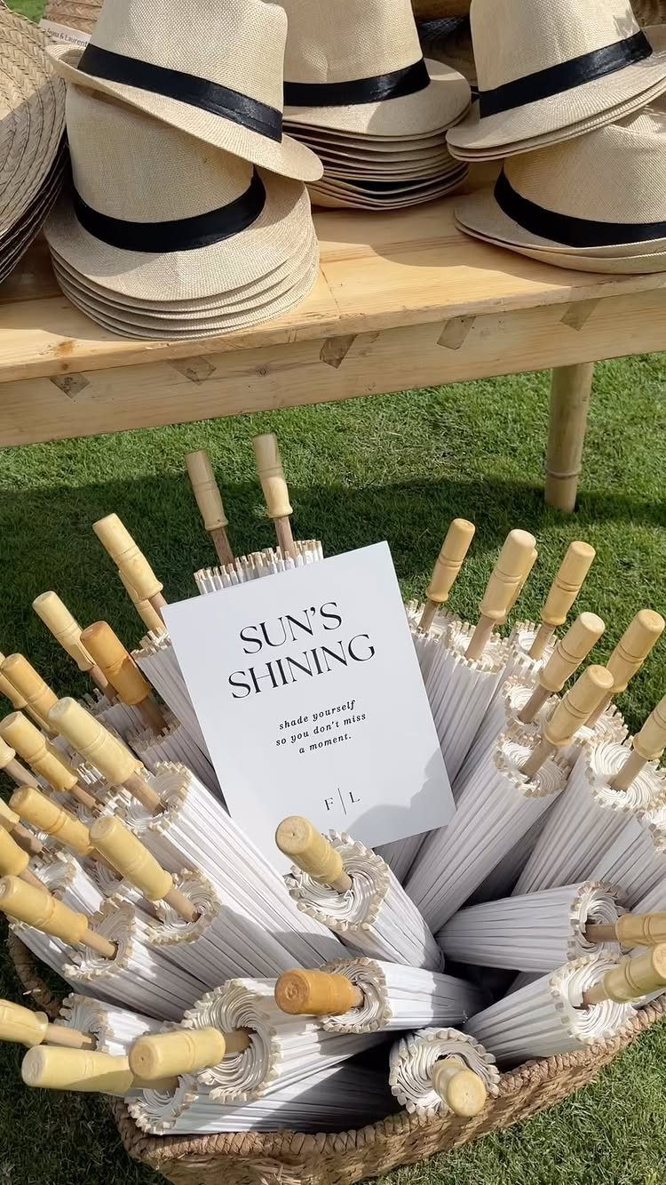 White folded parasols in a wicker basket with straw hats on a table.