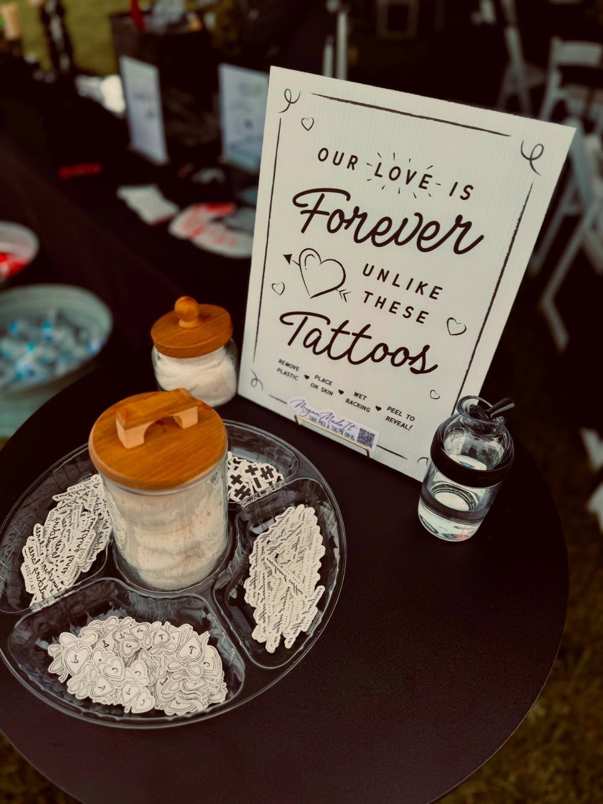 Temporary tattoos in a glass tray next to a wedding sign on a table
