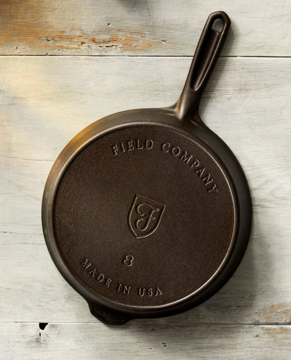 Black cast-iron skillet resting on a white weathered wooden background.
