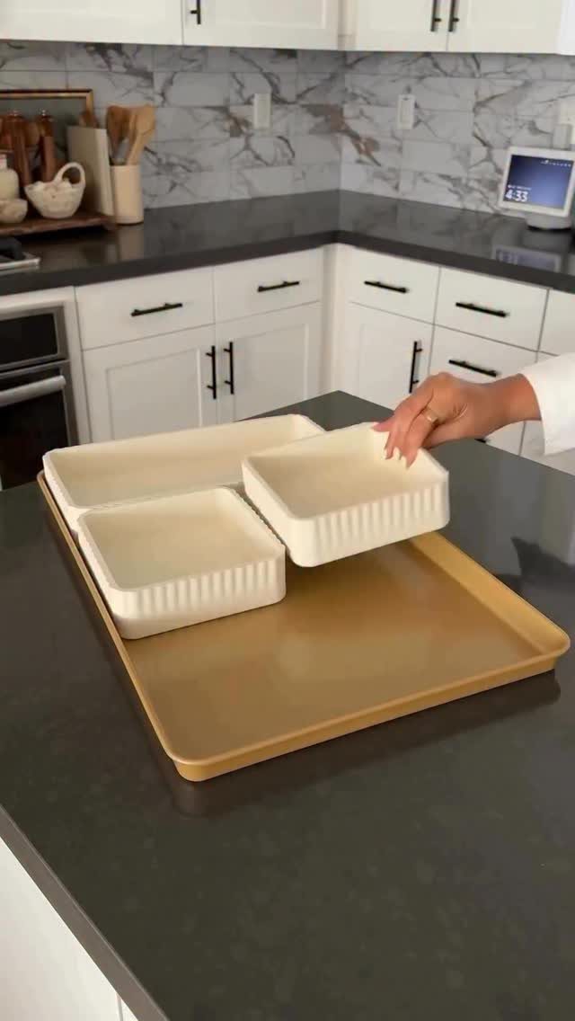 White ceramic baking dishes on a tan tray on a dark kitchen counter