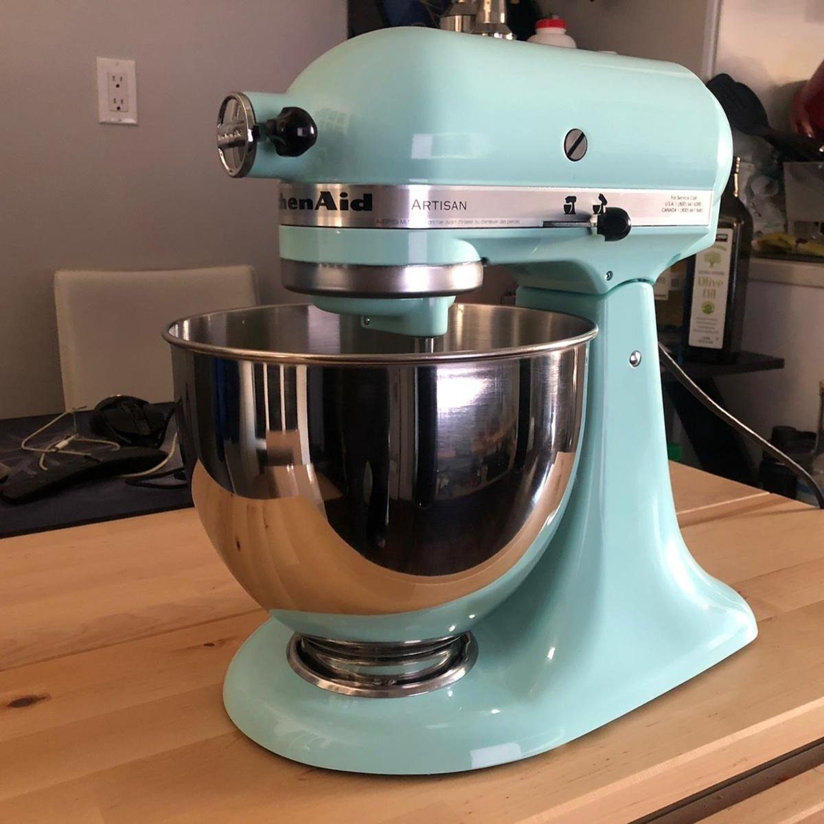 Light blue stand mixer with a stainless steel bowl on a wooden counter.