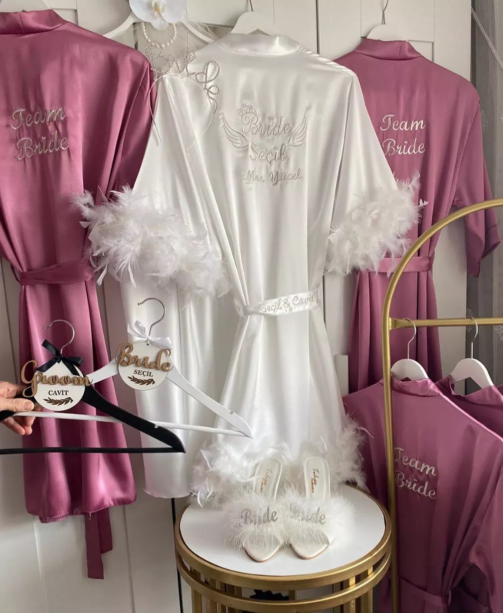 Satin bridal robes in white and mauve with feather trim and embroidery.