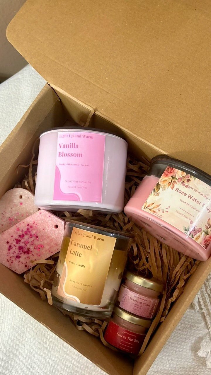 Scented candles and wax melts arranged in a cardboard gift box with filler.
