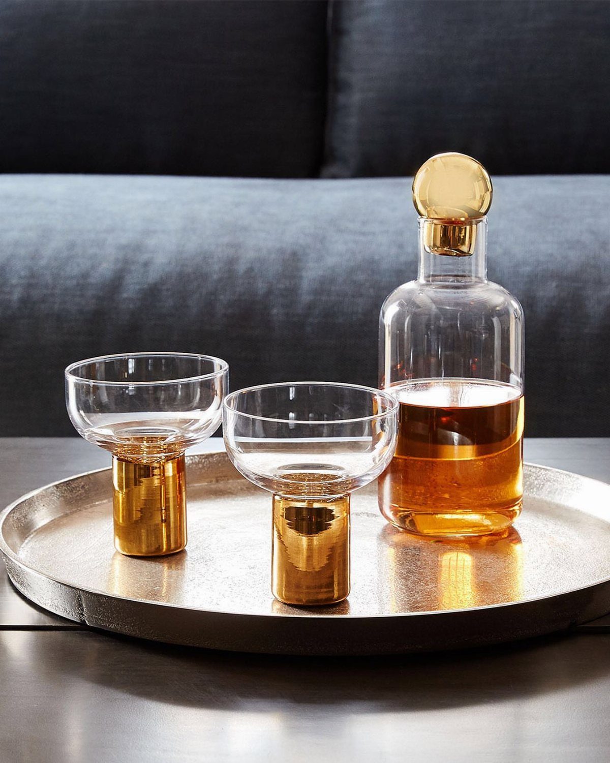 Glass decanter and two gold-based glasses on a silver tray