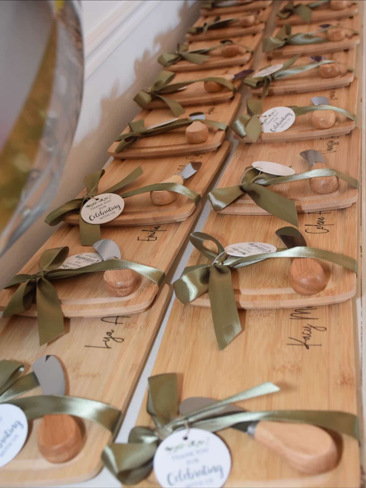 Small wooden cheese boards with knives tied in gold ribbons as wedding favors.