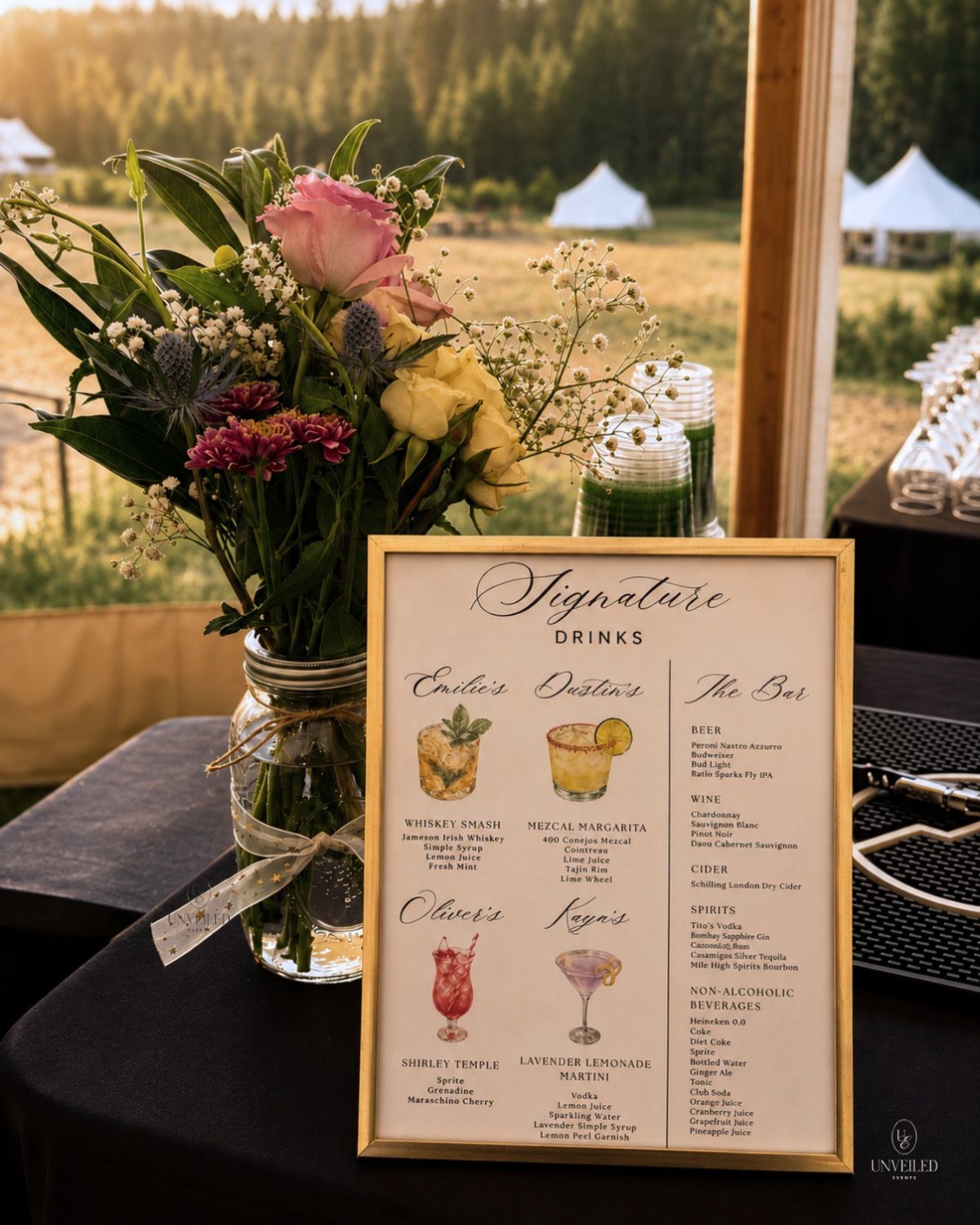 Gold-framed signature drinks bar sign next to a floral arrangement on a table.