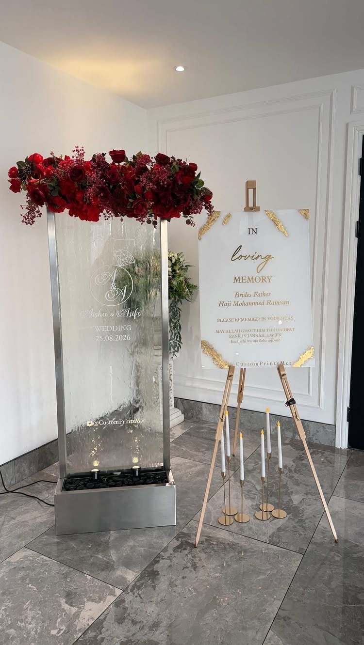 Memory sign on a wooden easel with red roses and white candles.