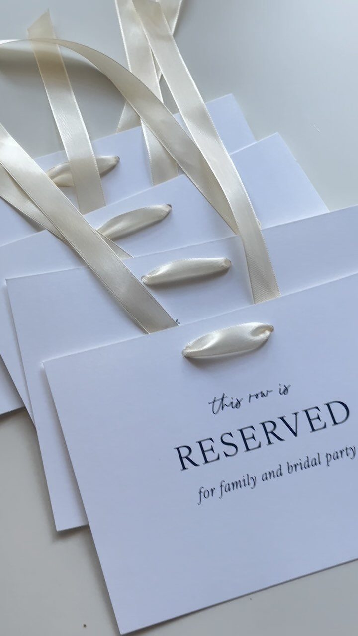 Reserved seating signs with white satin ribbons for family and bridal party.