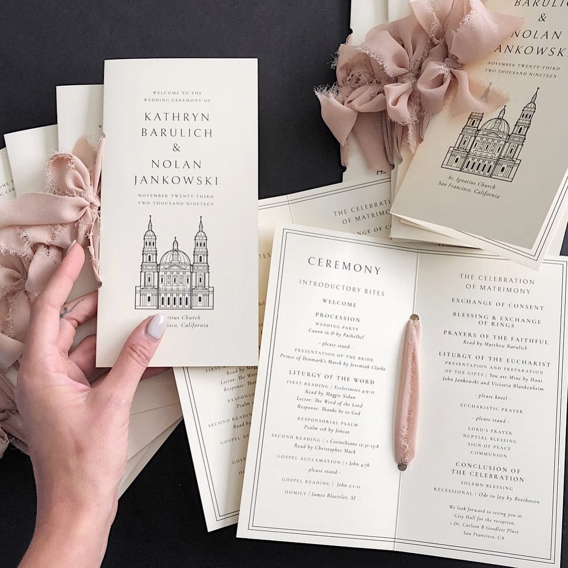 Wedding ceremony program with church illustration held by a hand among matching stationery.