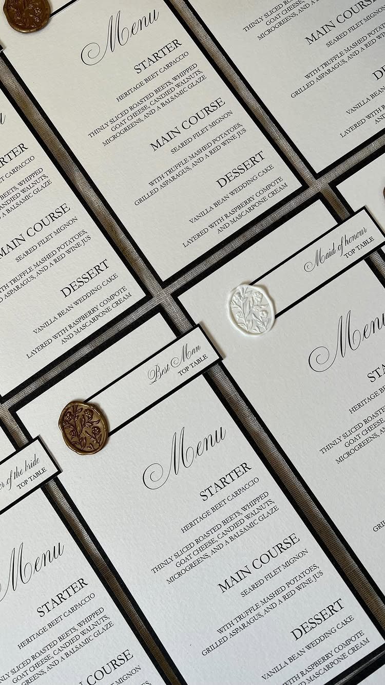 White wedding menu cards with black text and wax seals on dark background